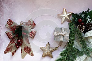 Golden stars, gift box, christmas tree branch and decorations on light pink textured background.