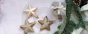 Golden stars, gift box, christmas tree branch and decorations on light pink textured background.