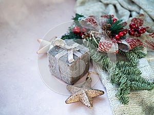 Golden stars, gift box, christmas tree branch and decorations on light pink textured background. Selected focus