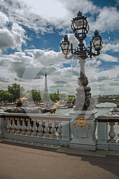 Golden statue and lighting post adorning the Alexandre III bridge over the Seine River and Eiffel Tower in Paris.