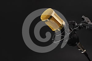 Golden studio condenser microphone on a black background