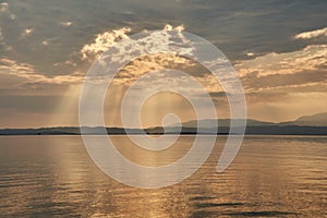 Sunset at lake Garda in Italy, golden sun behind clouds, Sirmione