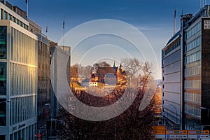 Golden sun light shine on old building at center with new building around in Oslo Norway