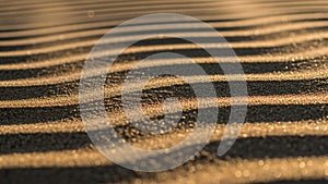 Shadows over rippled sand, creating a pattern of alternating light