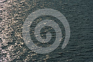 Golden sunlight reflected in a waves at sunset, dark contrast background seascape, top view, beautiful sea