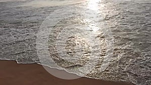 Golden sunlight reflecting on a beach. Sun shining in the evening - waves breaking on the shore. golden sunlight at beach.