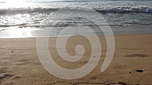 Golden sunlight reflecting on a beach. Sun shining in the evening - waves breaking on the shore. golden sunlight at beach.