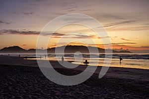 Golden sunrise above Campeche Island with surfers walking along the shore