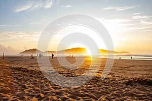 Golden sunrise above Campeche Island with surfers walking along the shore