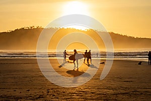 Golden sunrise above Campeche Island with surfers walking along the shore