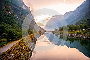 Golden sunrise in the mountains, Gudvangen Norway with reflection in the water of the fjord. The horizontal frame.