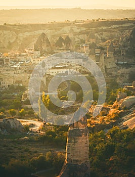 Golden sunrise over Goreme town in Cappaocia front side sunlight directional with balloons on air in sunny hazy autumn calm