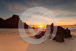 Golden sunrise warm sunlight on the remote rocky beach