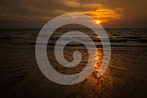 A golden sunset on a beach in Koh Lanta, Thailand, the colour of the sun reflecting on the wet sand