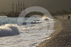 Golden sunset on the beach of the Mediterranean Sea. A yacht is moored at the shore