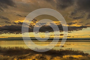 Golden sunset with clouds reflected in the water over Lake Albufera