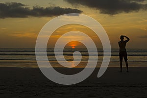 Golden Sunset at Kuta Beach with the silhouette of a photographer taking a photo at sunset
