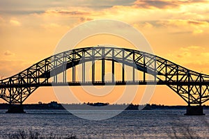Golden sunset light over a steel tied arch bridge. Fire Island Inlet Bridge