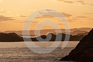 Golden sunset over an archipelago with wind turbines in the horizon