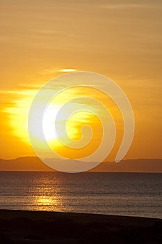 Golden sunset over beach and mountain horizon