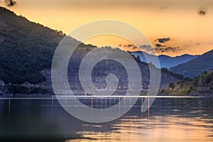 Golden, sunset sky with fluffy clouds over reflective, silky lake