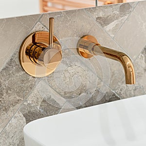 Golden tap in bathroom washbasin, close-up