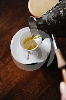 Golden tea fenugreek seeds decoction poured from a cezve into a white cup