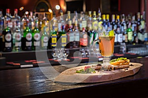 Golden tea in transparent glass with mint, cinnamon and strawberries on wooden tree trunk. Wooden bar counter, blurred background