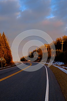 Golden telephone poles by rural highway at sunset