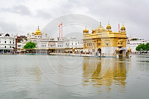 Golden Temple known as Harmandir Sahib in Amritsar, Punjab, India in cloudy weather with grey sky reflected in water
