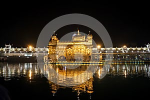 Golden temple with reflection in the water at night