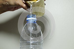 Pouring water from the golden Thai stayle glass of water into bottle of water with hand photo