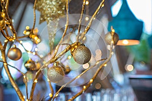 Golden toy balls hanging on artificial tree branches decoration