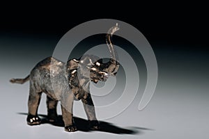 Golden toy elephant with blood on tusks on grey background