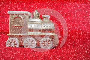 Golden toy train locomotive on a red and pink gradient background. New Year or Christmas card. Icicles and snow on a