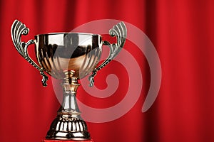 Golden trophy cup over red background
