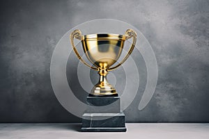 Golden Trophy in front of the gray wall. Winner or a champion concept. Minimalistic