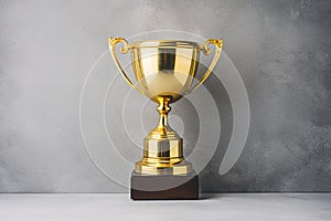 Golden Trophy in front of the gray wall. Winner or a champion concept. Minimalistic