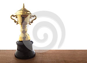 Golden trophy on wooden table isolated over white background. Winning awards with copy space.