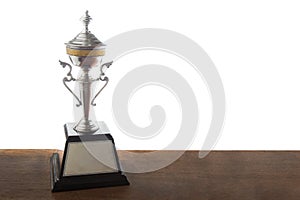 Golden trophy on wooden table isolated over white background. Winning awards with copy space.