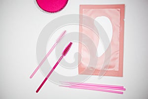 Golden tweezers, microbrush, finished bundles, pink brushes, eye patches
