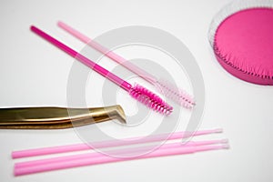 Golden tweezers, microbrush, finished bundles, pink brushes, eye patches