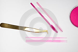 Golden tweezers, microbrush, finished bundles, pink brushes, eye patches