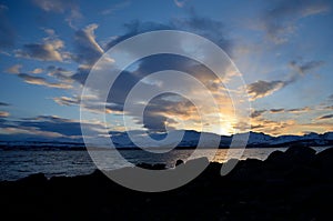 Golden vibrant sunset over snowy mountain and fjord landscape