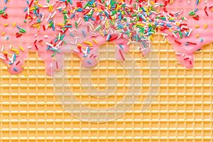 Golden waffle texture with pink icing and sprinkles, background for your design photo