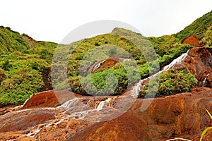 Golden Waterfall flowing over rust-colored rocks