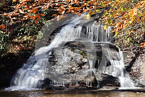 Golden waterfall: Waterfall framed with yellow and orange fall leaves and water, horizontal