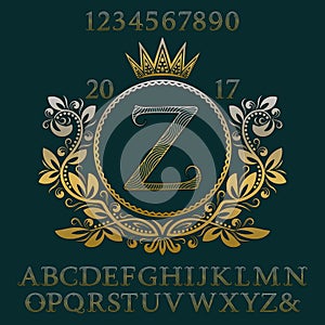 Golden wavy patterned letters and numbers with initial monogram in coat of arms form. Elegant font and elements kit for logo