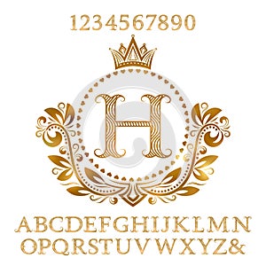 Golden wavy patterned letters and numbers with initial monogram in coat of arms form. Shining font and elements kit for logo