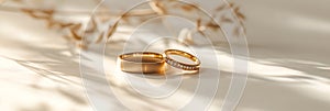 Golden wedding bands with a matte finish on creamy silk. 2 golden wedding rings with diamonds on smooth fabric. Matte gold rings